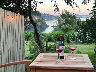 a wooden table with a bottle of wine and a glass at Sea Spray in St Austell