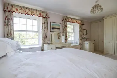 a bedroom with a large white bed and two windows at Temple House in Truro