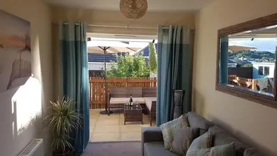a living room with a couch and a sliding glass door at Tolcarne Reach in Newquay