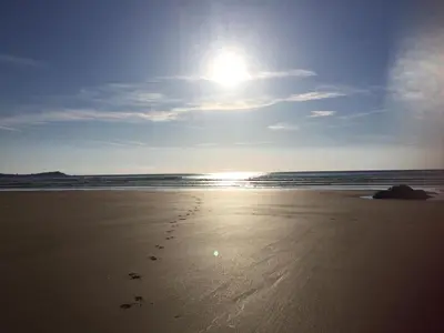 a beach with footprints in the sand and the ocean at Tolcarne Reach in Newquay