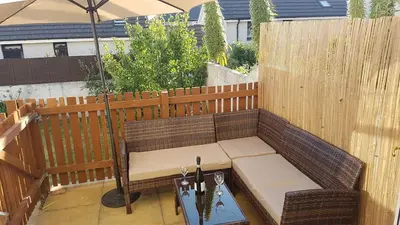 a patio with a bench and an umbrella on a fence at Tolcarne Reach in Newquay