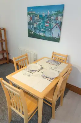 a dining room table with four chairs and a painting on the wall at Utopia Apartments in Perranporth