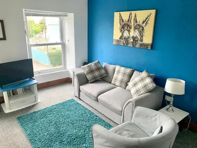 a living room with a couch and a tv at Utopia Apartments in Perranporth