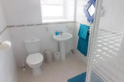 a white bathroom with a toilet and a sink at Utopia Apartments in Perranporth