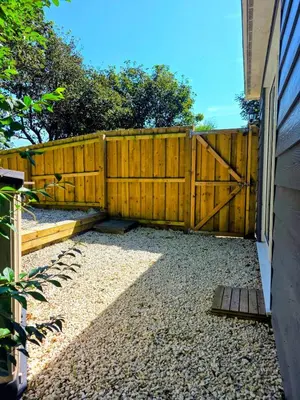 a fence with a wooden gate next to a house at The Captains Quarters in Porthtowan