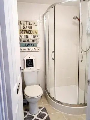 a bathroom with a shower and a white toilet at The Captains Quarters in Porthtowan