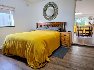 a bedroom with a bed with a yellow blanket and a mirror at The Captains Quarters in Porthtowan