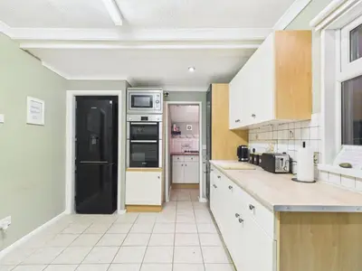 a kitchen with white cabinets and a black refrigerator at Riviera Cottage - Cornwall in Portreath