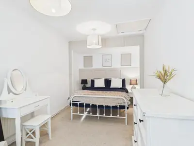 a white bathroom with a bed and a sink at Riviera Cottage - Cornwall in Portreath