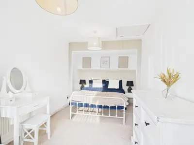 a white bedroom with a bed and a sink at Riviera Cottage - Cornwall in Portreath