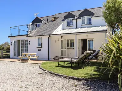 a white house with two chairs in front of it at Atlantic View in Bude