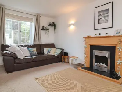 a living room with a brown couch and a fireplace at Atlantic View in Bude