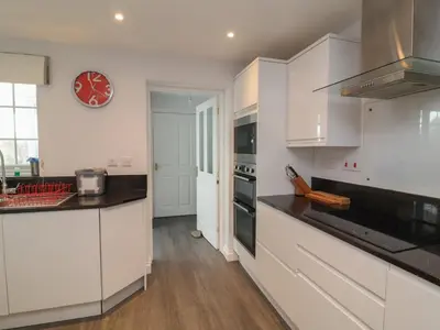 a kitchen with white cabinets and a clock on the wall at Atlantic View in Bude