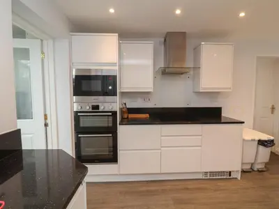a kitchen with white cabinets and a black counter top at Atlantic View in Bude