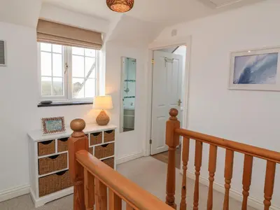 a hallway with a staircase with a lamp and a window at Atlantic View in Bude