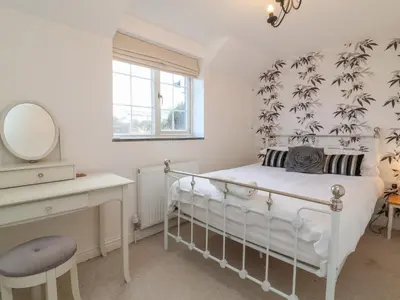 a bedroom with a bed and a desk and a mirror at Atlantic View in Bude