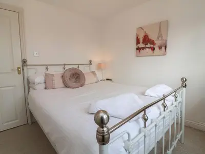a bedroom with a bed with white sheets and pink pillows at Atlantic View in Bude
