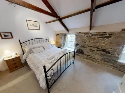 a bedroom with a bed and a stone wall at Jowders Cottage in Marazion