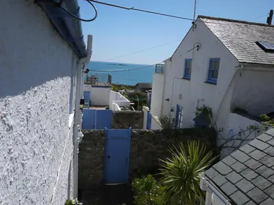 an alley between two white buildings with a blue door at Jowders Cottage in Marazion