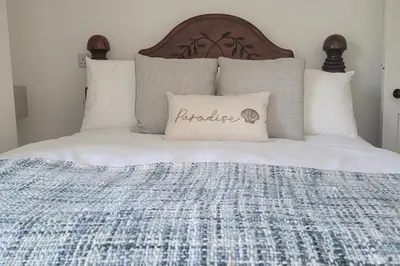 a bed with a pillow with the word paradise on it at Looe Cottage - Seaside views log fire sleeps 4 in Looe