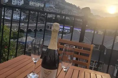 a bottle of wine sitting on a table with two glasses at Looe Cottage - Seaside views log fire sleeps 4 in Looe