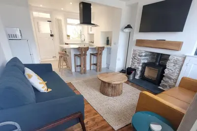 a living room with a blue couch and a fireplace at Looe Cottage - Seaside views log fire sleeps 4 in Looe