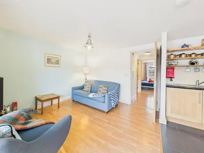 a living room with a blue couch and a kitchen at Penryn Quayside Apartment – 1-bed, Fully Equipped Waterside base in Penryn