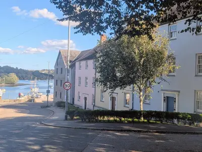 a street with two white buildings next to a body of water at Penryn Quayside Apartment – 1-bed, Fully Equipped Waterside base in Penryn