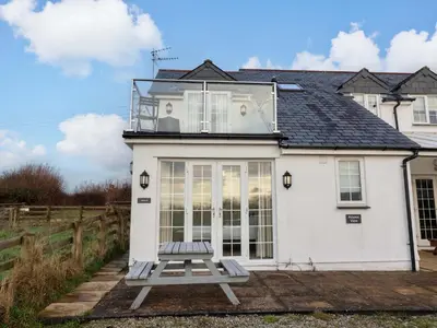 a white house with a balcony on top of it at Atlantic View Annex in Bude