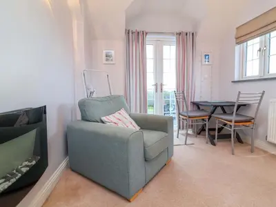 a living room with a blue chair and a table at Atlantic View Annex in Bude