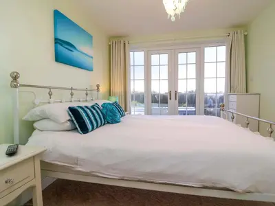 a bedroom with a large white bed with blue pillows at Atlantic View Annex in Bude