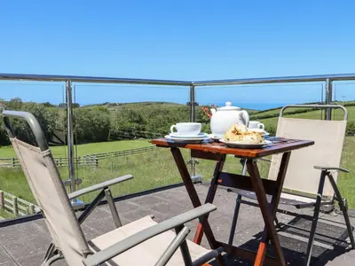 a table with a tea pot and chairs on a balcony at Atlantic View Annex in Bude