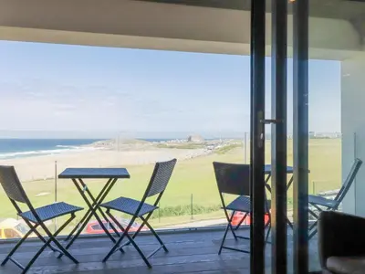 a balcony with chairs and a table and a view of the ocean at Beach View Fistral in Newquay