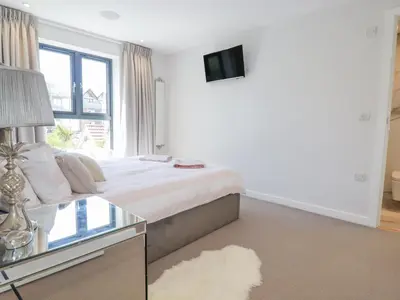 a white bedroom with a bed and a window at Beach View Fistral in Newquay