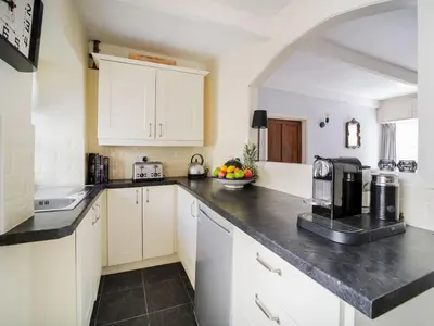 a kitchen with white cabinets and a black counter top at Kernyck in Port Isaac