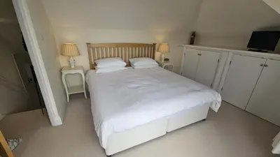 a bedroom with a large white bed with two lamps at Highlands in Saint Mawes