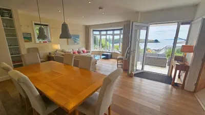 a dining room and living room with a wooden table at Highlands in Saint Mawes