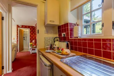 a kitchen with a sink and a red tiled wall at 1 Bed in Two Waters Foot oc-a27332 in Warleggan