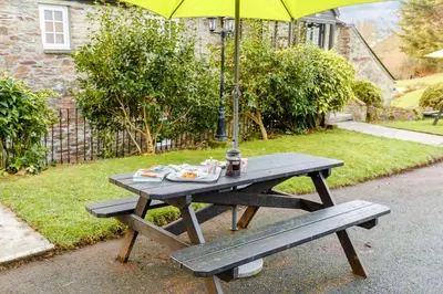 a picnic table with an umbrella and a bench at 1 Bed in Two Waters Foot oc-a27332 in Warleggan