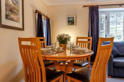a dining room with a table with chairs and a blue couch at 2 Bed in Two Waters Foot oc-s27334 in Warleggan