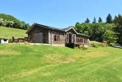 a log cabin on a hill with a green field at 3 Bed in Two Waters Foot oc-m27335 in Cardinham