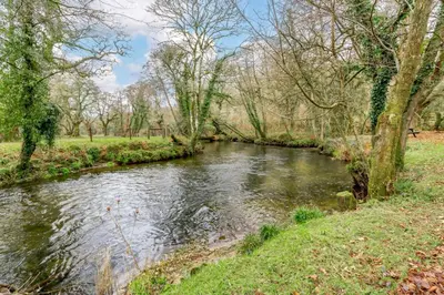 a river in a park with trees and grass at 3 Bed in Two Waters Foot oc-m27335 in Cardinham