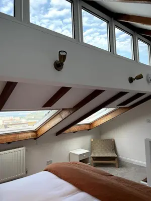 a bedroom with large windows and a bed and a chair at Central loft apartment sea views in Falmouth