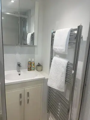 a bathroom with a sink and a shower with towels at Central loft apartment sea views in Falmouth