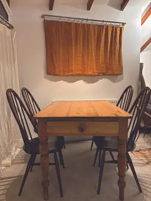 a wooden table and chairs in a room with a curtain at Central loft apartment sea views in Falmouth