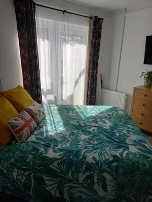 a bed with a green and white comforter and a window at Garden room in St Ives