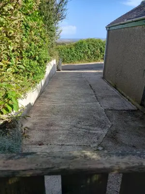 a wooden bench sitting on a sidewalk next to a road at Garden room in St Ives