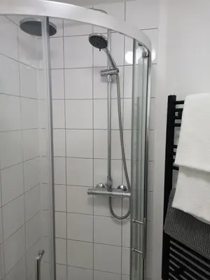 a shower in a bathroom with white tiles at Garden room in St Ives
