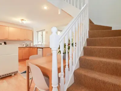a kitchen and dining room with a table and stairs at Acorns in Falmouth