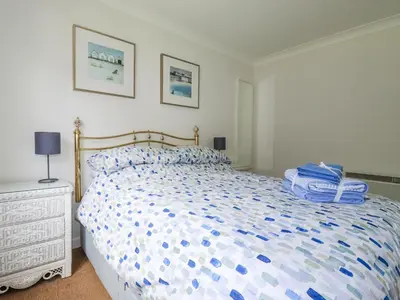 a bedroom with a bed with a blue and white comforter at Acorns in Falmouth